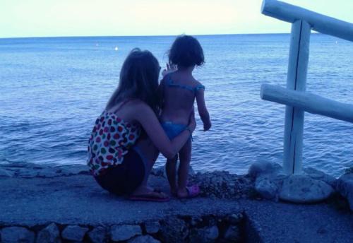 a woman and a child sitting next to the water at Hotel Ristorante Maga Circe in San Felice Circeo