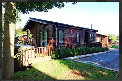uma cabana de madeira com um alpendre e uma casa em Brambles Holiday Lodges em Paignton
