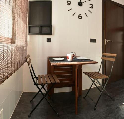 un tavolo con due sedie e un orologio su una parete di BONITO AP CENTRICO PATIO WIFI PARKING GRATIS. a Granada