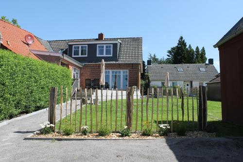 a fence in front of a house with a yard at Tant Berta´s Huus in Krummhörn