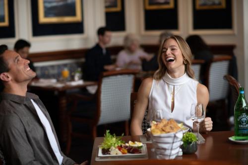 a man and a woman sitting at a table with a plate of food at Boston Harbor Hotel in Boston