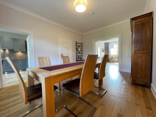 jadalnia z drewnianym stołem i krzesłami w obiekcie Saar-Apartments w mieście Merzig
