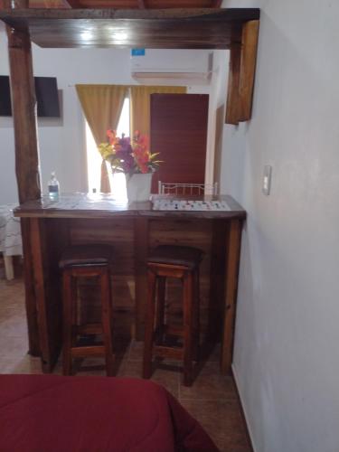a kitchen with a counter with stools and a vase of flowers at Sol de Belen in San José
