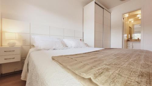 a white bedroom with a large bed and a mirror at Apartamento 50m2 Hospital Einstein Morumbi in Sao Paulo