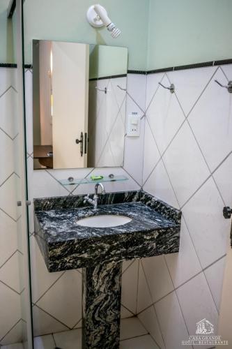 a bathroom with a marble sink and a mirror at Hotel Casa Grande Itapira in Itapira
