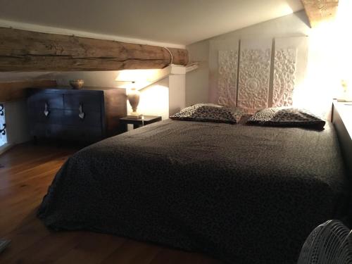 sypialnia z dużym czarnym łóżkiem i drewnianą podłogą w obiekcie Ravissant studio climatisé Gambetta Miséricorde au cœur de Saint-Tropez w Saint-Tropez