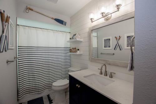 een badkamer met een wastafel, een toilet en een spiegel bij Sunrise on Lake Idylwild in Winter Haven