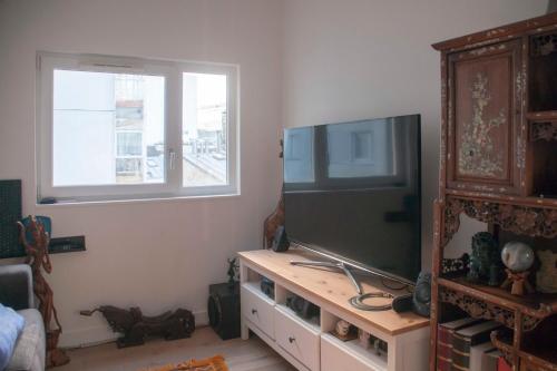 un salon avec une grande télévision à écran plat dans l'établissement Nice Apt With Balcony Near Centquatre Paris, à Paris