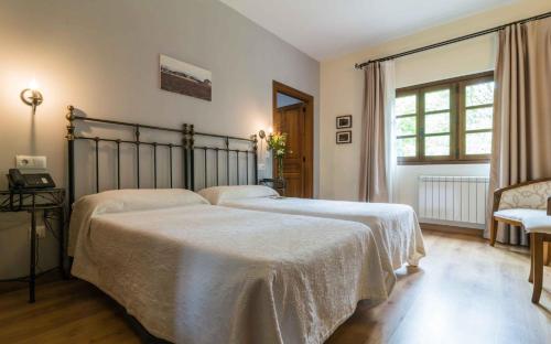 San Salvador的住宿－Alesga Hotel Rural - Valles del Oso -Asturias，一间卧室设有两张床和窗户。