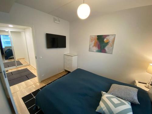 um quarto com uma cama azul e uma televisão em Modern two bedroom apartment near Helsinki Airport em Vantaa