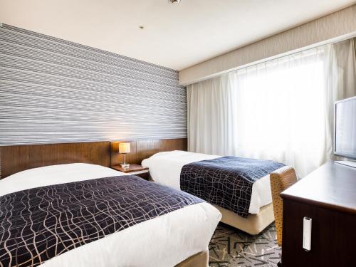 a hotel room with two beds and a window at APA Hotel Matsuyamajo Nishi in Matsuyama