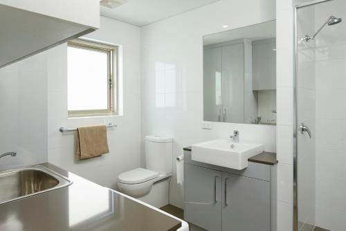 un bagno bianco con lavandino e WC di Baileys Serviced Apartments a Perth