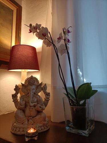 a table with a lamp and a vase with flowers at Tottam Art & Healthy Garden in Málaga