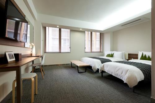 a hotel room with two beds and a desk and windows at Metro Hotel Myeongdong in Seoul