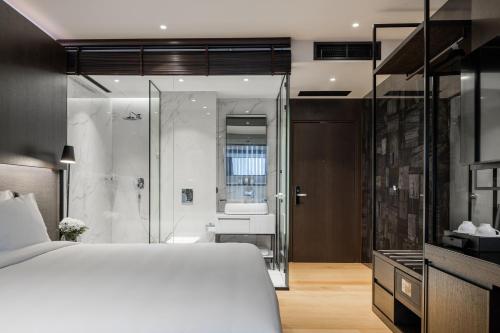 a bedroom with a white bed and a shower at Hotel MANAMI in Pristina