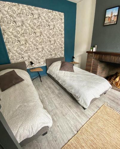 une chambre avec deux lits et une cheminée dans l'établissement La Maison Sévigné - Appart Hôtel - N°1, à Béthune