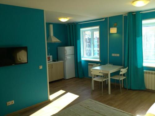 een keuken met blauwe muren en een tafel en stoelen bij Apartments near Circus in Novosibirsk