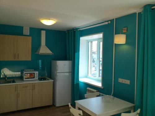 een keuken met blauwe muren en een tafel en een raam bij Apartments near Circus in Novosibirsk