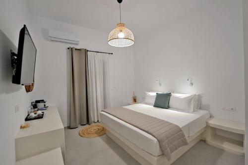a white bedroom with a bed and a television at Kleri's apartments 5 in Tinos Town