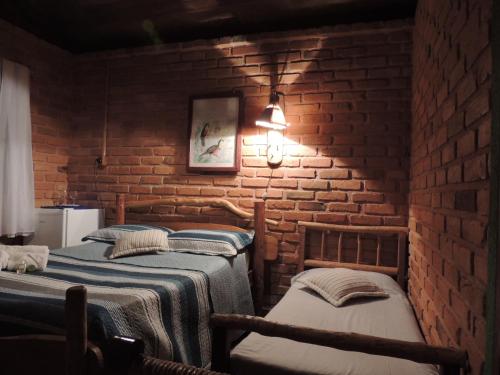 twee bedden in een kamer met een bakstenen muur bij Reserva Canto da Vida Chalés e Camping in Lima Duarte