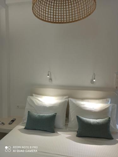 a bed with white pillows and a chandelier above it at Kleri's apartments 2 in Tinos Town