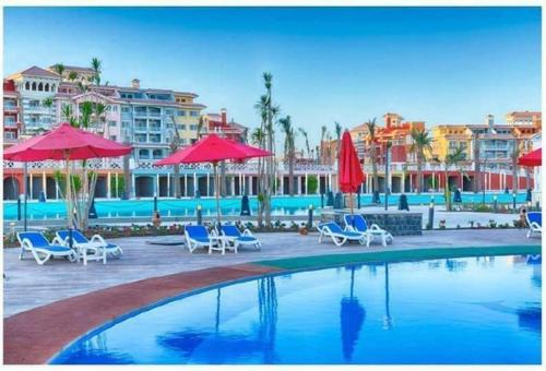 a swimming pool with blue chairs and umbrellas at easy rent in porto sharm in Sharm El Sheikh