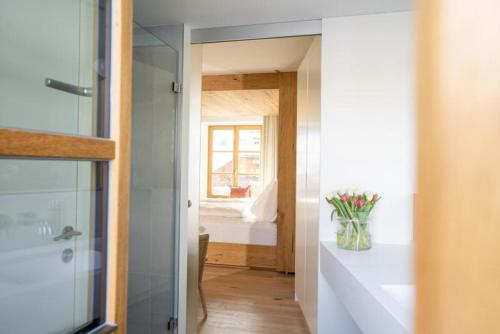 a bathroom with a shower and a vase of flowers on a counter at Mesnerhaus & Gourmetrestaurant Mesnerhaus mit 4 Hauben in Mauterndorf