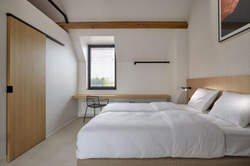 una camera da letto con un grande letto bianco e una finestra di DOS22 Vakantiewoning I De Haan Wenduine a Zuienkerke
