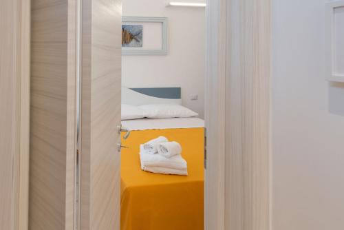 een kamer met een bed en handdoeken op een gele tafel bij L'Approdo - Bilocale Centralissimo a San Benedetto del Tronto in San Benedetto del Tronto