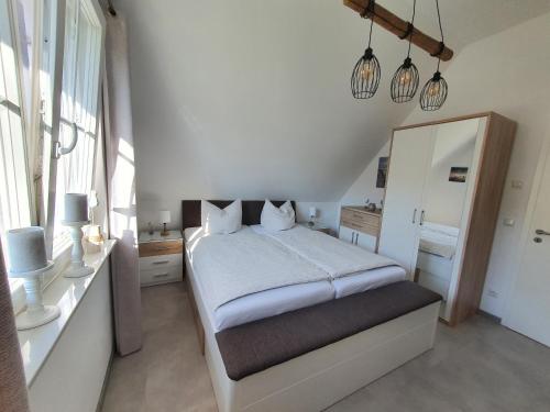 a white bedroom with a bed and a mirror at Haus Möwenkind in Zirchow