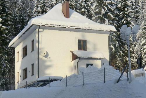 a house covered in snow with a fence and trees at Ferienhaus Lebenskraft in Pfaffetschlag