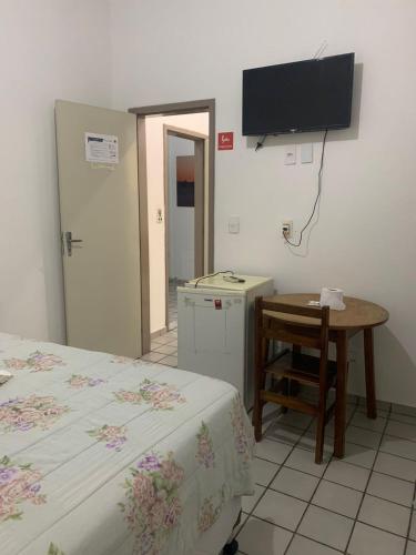 a room with a bed and a table and a television at Amarante Hotel in Juazeiro