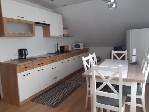 a kitchen with white cabinets and a table and chairs at DOM POD MARESZKĄ in Bartne