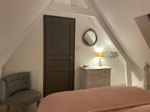 a bedroom with a bed and a chair and a mirror at les gites du grand saule in Tardinghen