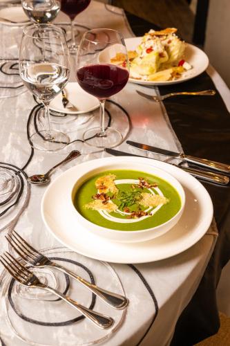 a table with a plate of green soup and glasses of wine at Novotel Mexico City Toreo in Mexico City