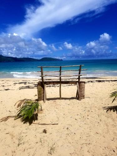 a bench sitting on the beach near the ocean at Solazul in Las Galeras