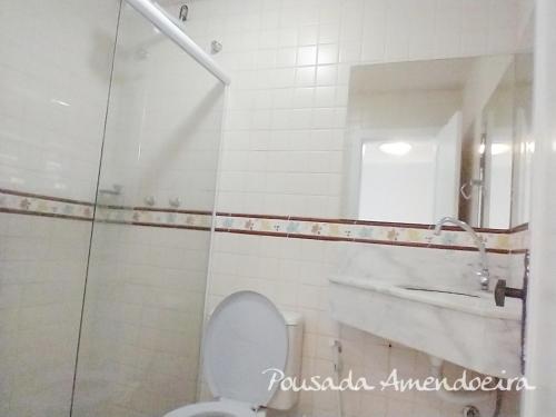 y baño con aseo, lavabo y espejo. en POUSADA AMENDOEIRA, en Búzios