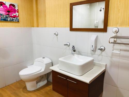 ein Badezimmer mit einem WC, einem Waschbecken und einem Spiegel in der Unterkunft Quito Terrace in Quito