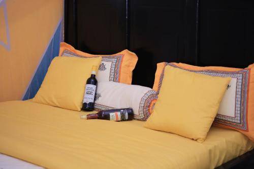 a bed with a bottle of wine and two pillows at Awooooo Accommodation Kampala in Kampala