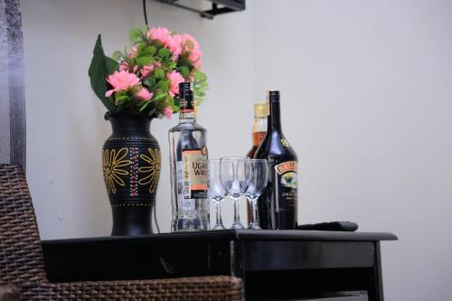 a table with bottles and glasses and a vase with flowers at Awooooo Accommodation Kampala in Kampala