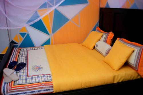 a bedroom with a bed with yellow sheets and pillows at Awooooo Accommodation Kampala in Kampala