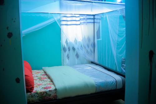 a small bed in a room with a canopy at Awooooo Accommodation Kampala in Kampala