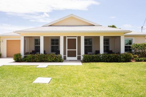 a house with a green lawn in front of it at Art Deco Themed Vacation Home w Sauna, Huge Terrace, & Outdoor BBQ Kitchen in Hallandale Beach