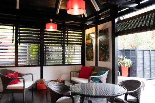 a patio with a table and chairs and windows at Domaine de la Palmeraie - Villas Lodge in Le Diamant