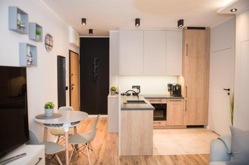 a kitchen with white cabinets and a table and chairs at Beautiful Days in Lodz in Łódź