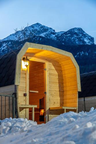 a wooden cabin in the snow with a mountain in the background at Garden Wellness Hotel S in Andalo
