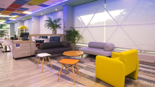 a lobby with yellow and blue furniture and tables at ibis budget Barranquilla in Barranquilla