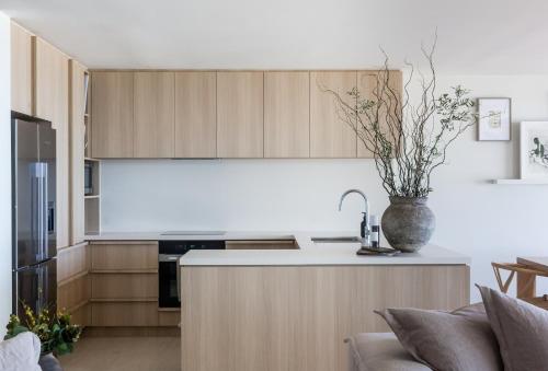 une cuisine avec des placards en bois et un vase avec une plante dans l'établissement Noosa Court Apartment 4, Noosa Heads, à Noosa Heads