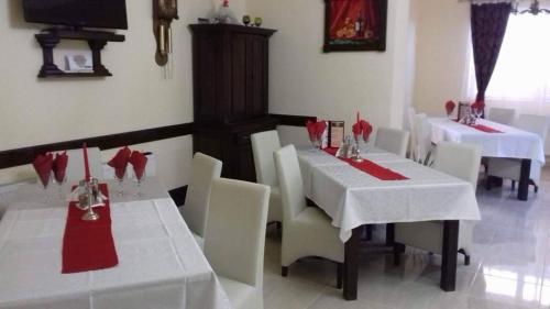 a restaurant with white tables and white chairs and red napkins at CASA ARDELEANULUI in Satu Mare