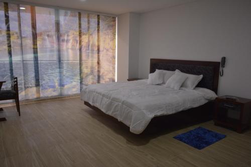 a bedroom with a bed and a large window at Hotel Prestigio JC in Sogamoso